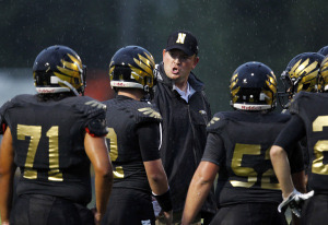 Adam Billings coaching North Bullitt football players on the sideline